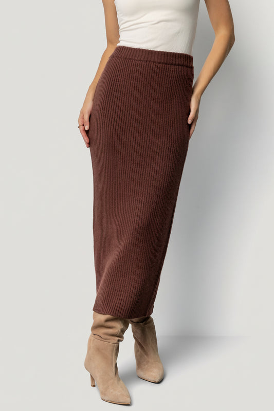 Model front view wearing the Blair rib knit midi skirt in mahogany, fitted through hips with raw hem and stretch waistband.