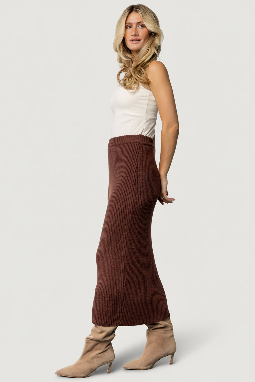 Flat lay of the Blair rib knit skirt in mahogany displaying the elasticized waistband, raw hem, and the garment's material characteristics.