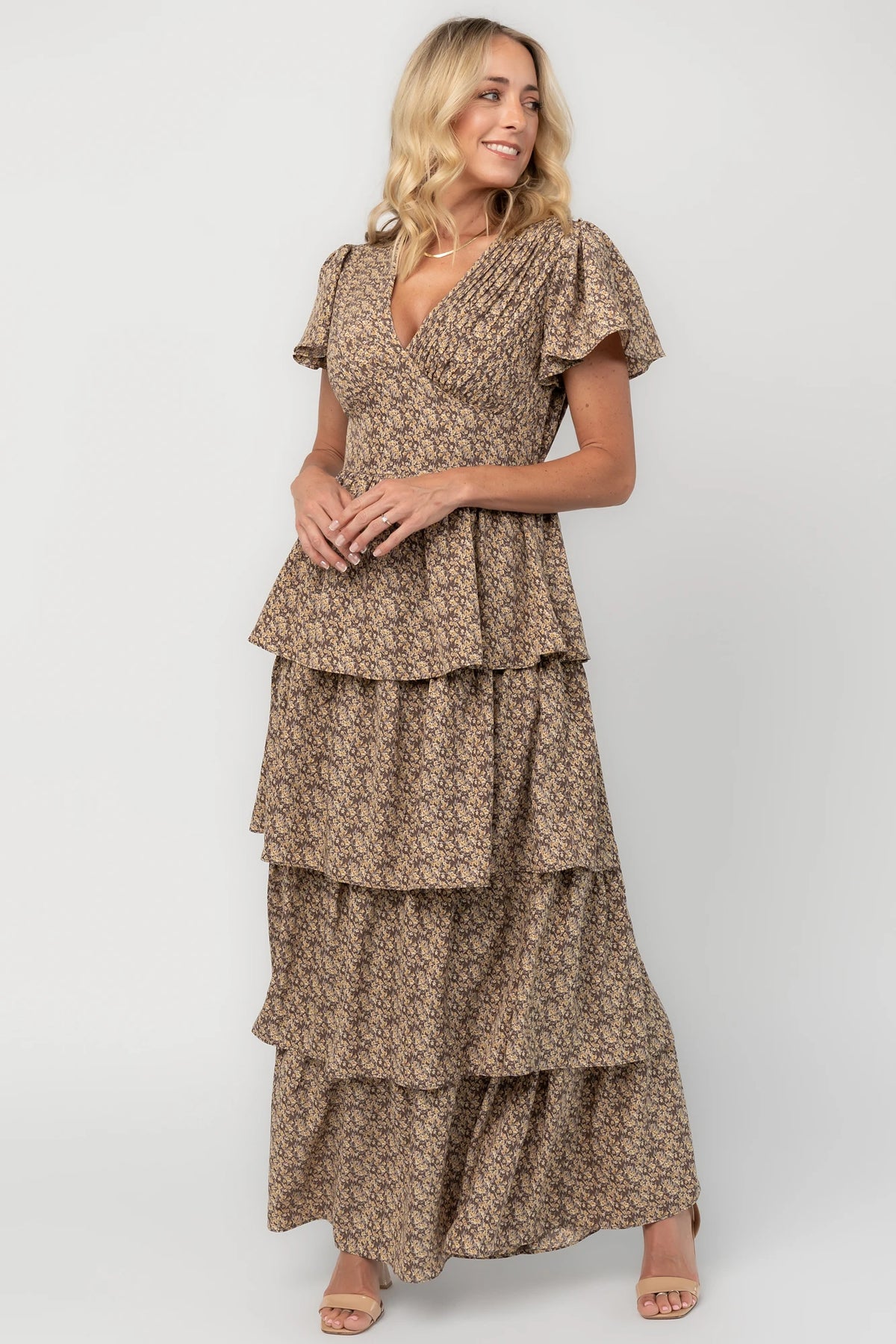 Brown floral maxi dress with a V-neckline, flutter sleeves, elastic back waist, and cascading tiered skirt.