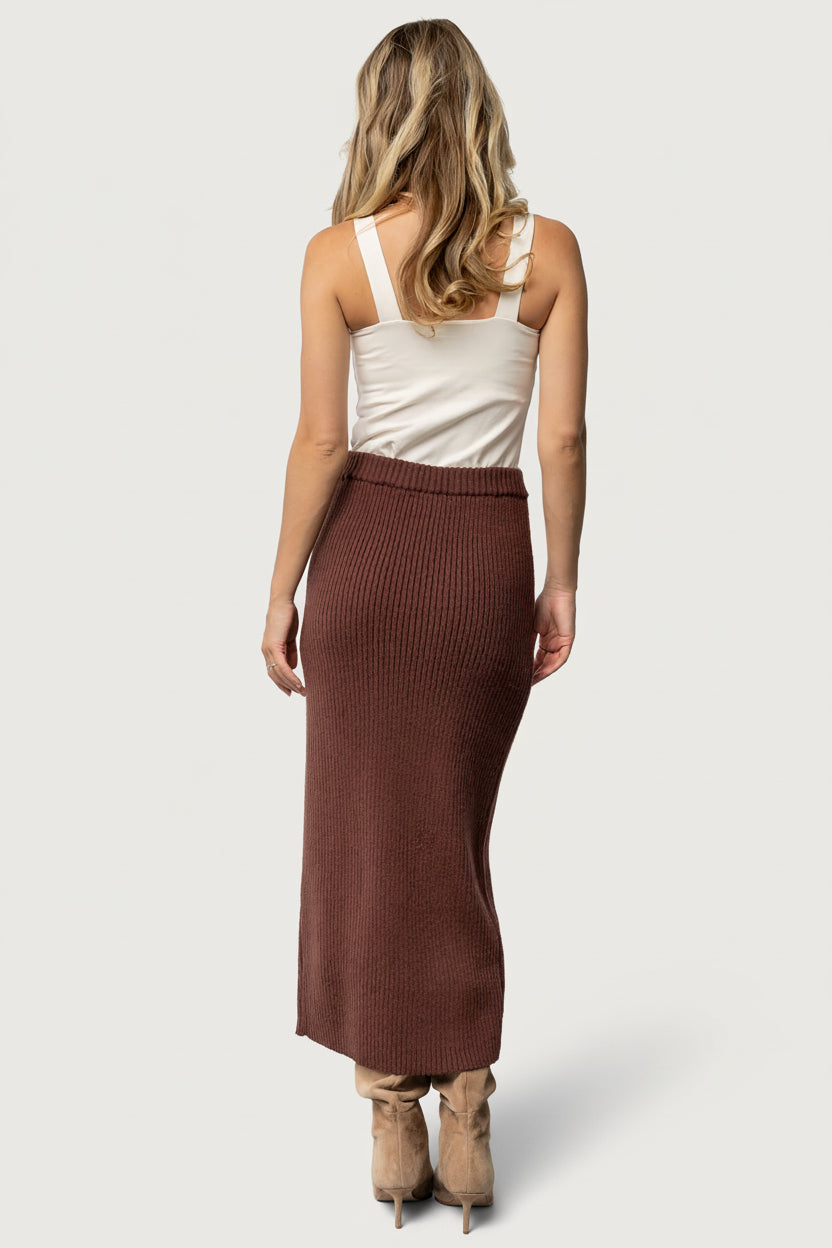 Back view of model in rib knit midi skirt highlighting fit through the hips and natural drape of the knit fabric.