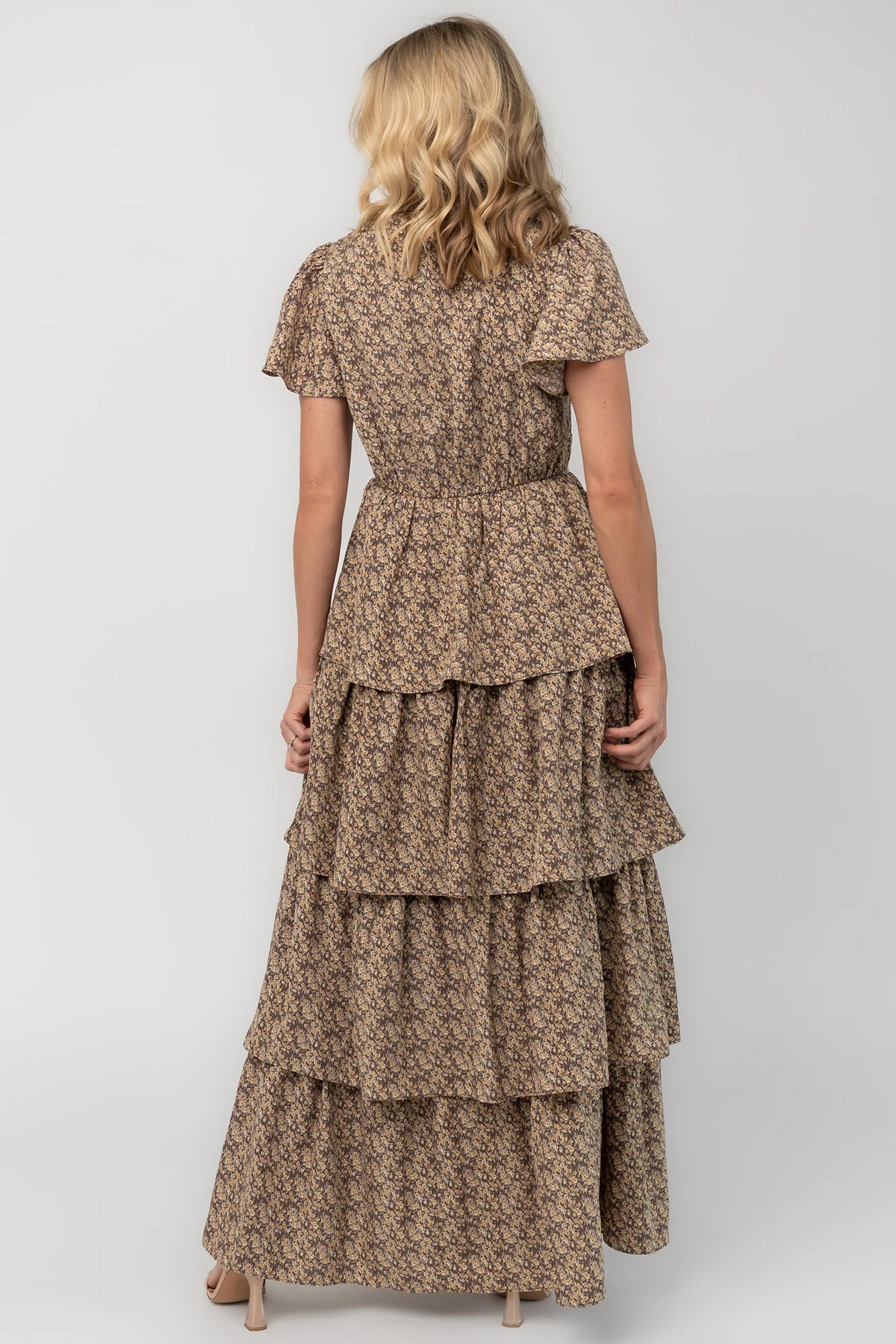 Brown floral maxi dress with a V-neckline, flutter sleeves, elastic back waist, and cascading tiered skirt.