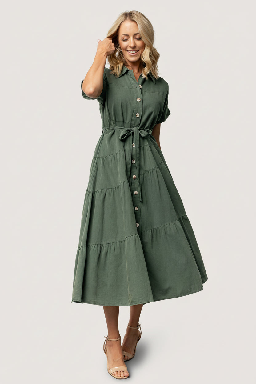 Three-quarter view of the washed green Logan Button Up Dress highlighting A-line tiered maxi skirt, diagonal seam detail, and lightweight unlined construction.