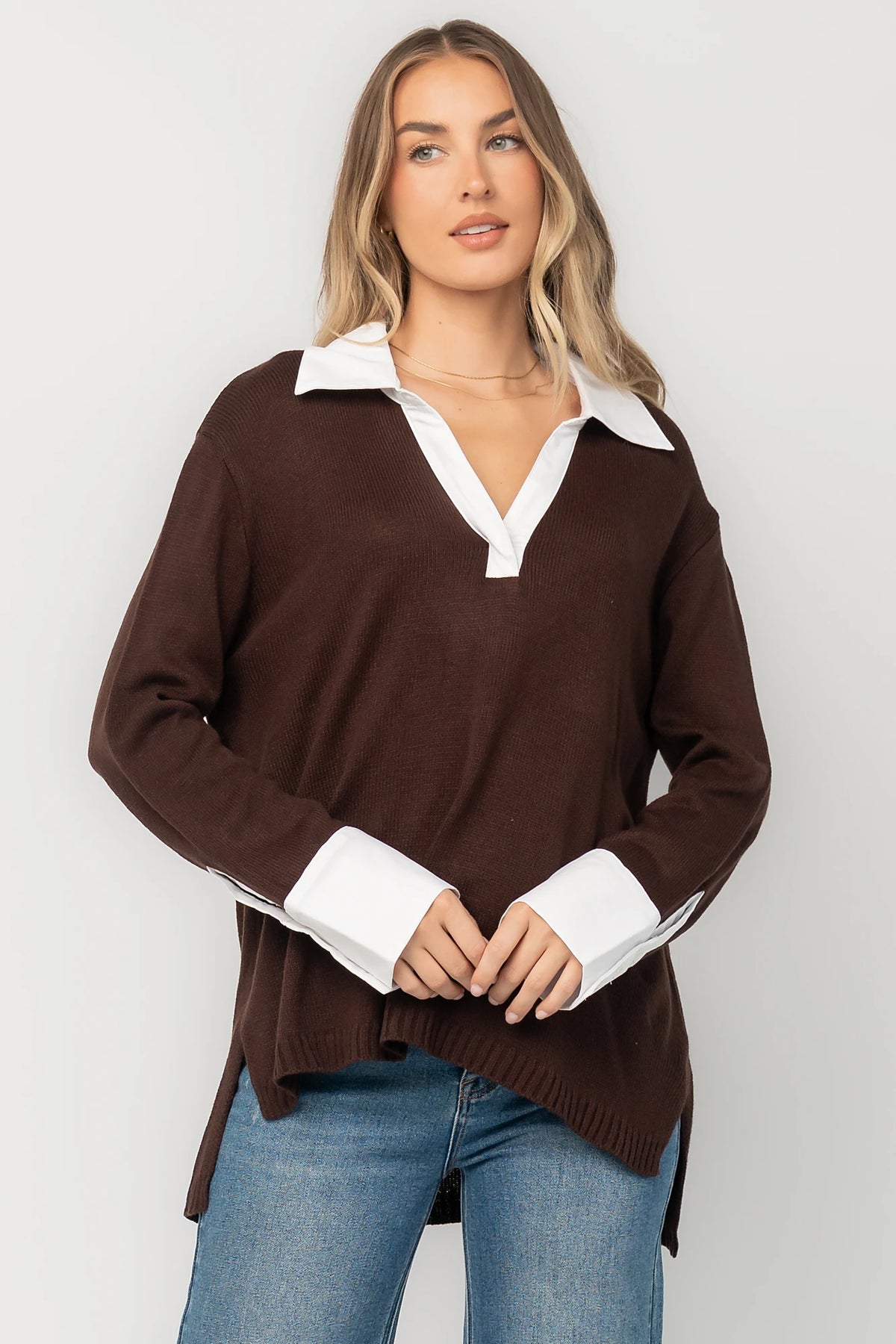 Chocolate sweater top with a contrast white collared neckline and cuffs, split V-neck, long sleeves, side hem slits, ribbed hem, and a relaxed fit.