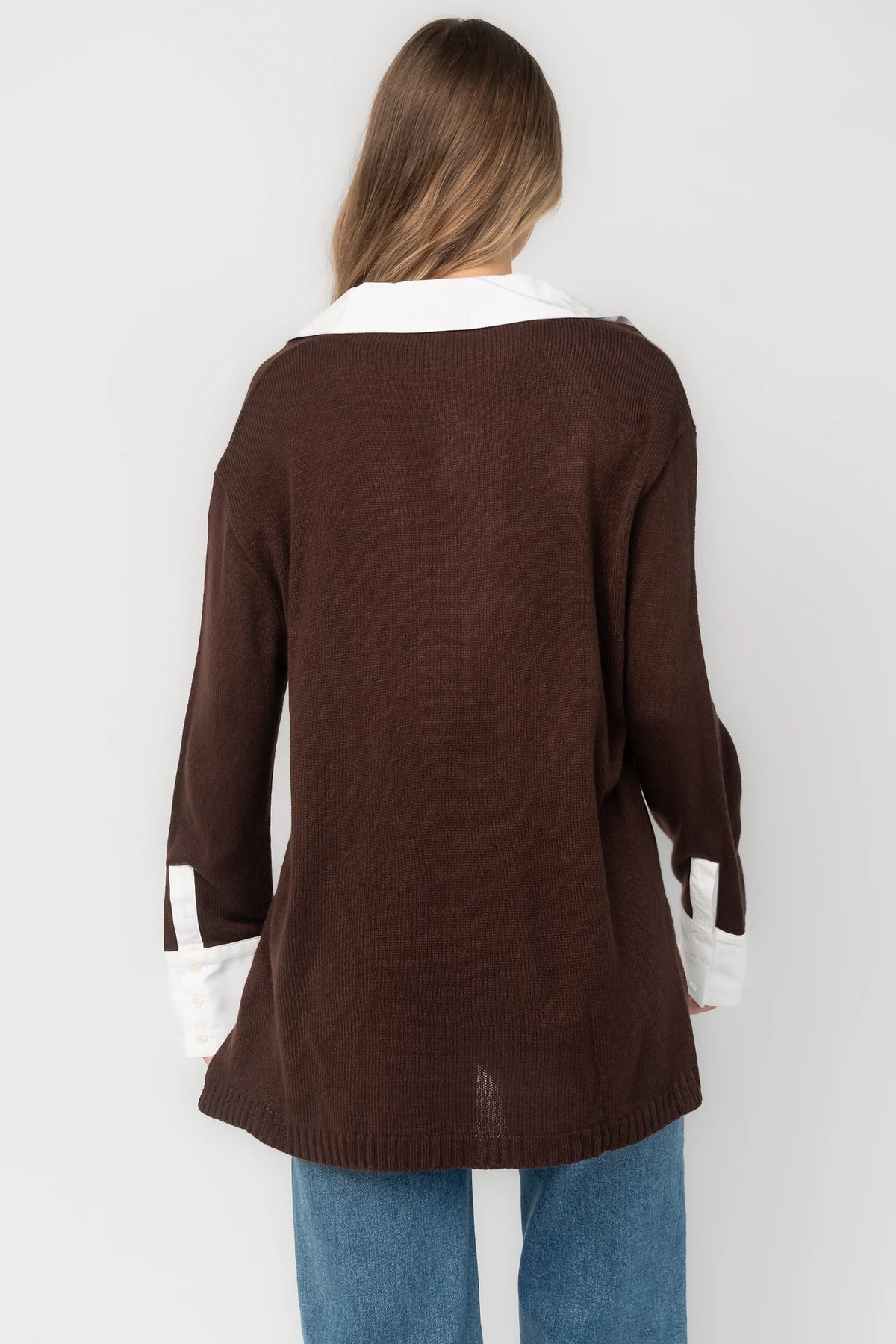 Chocolate sweater top with a contrast white collared neckline and cuffs, split V-neck, long sleeves, side hem slits, ribbed hem, and a relaxed fit.