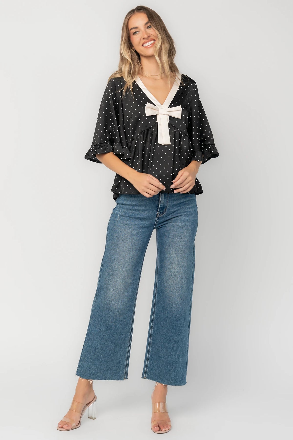 Carrie Bow Front Top in Black + Ivory Dot with contrast collar, bow detail, V-neck, ruffle sleeves, and peplum hem.