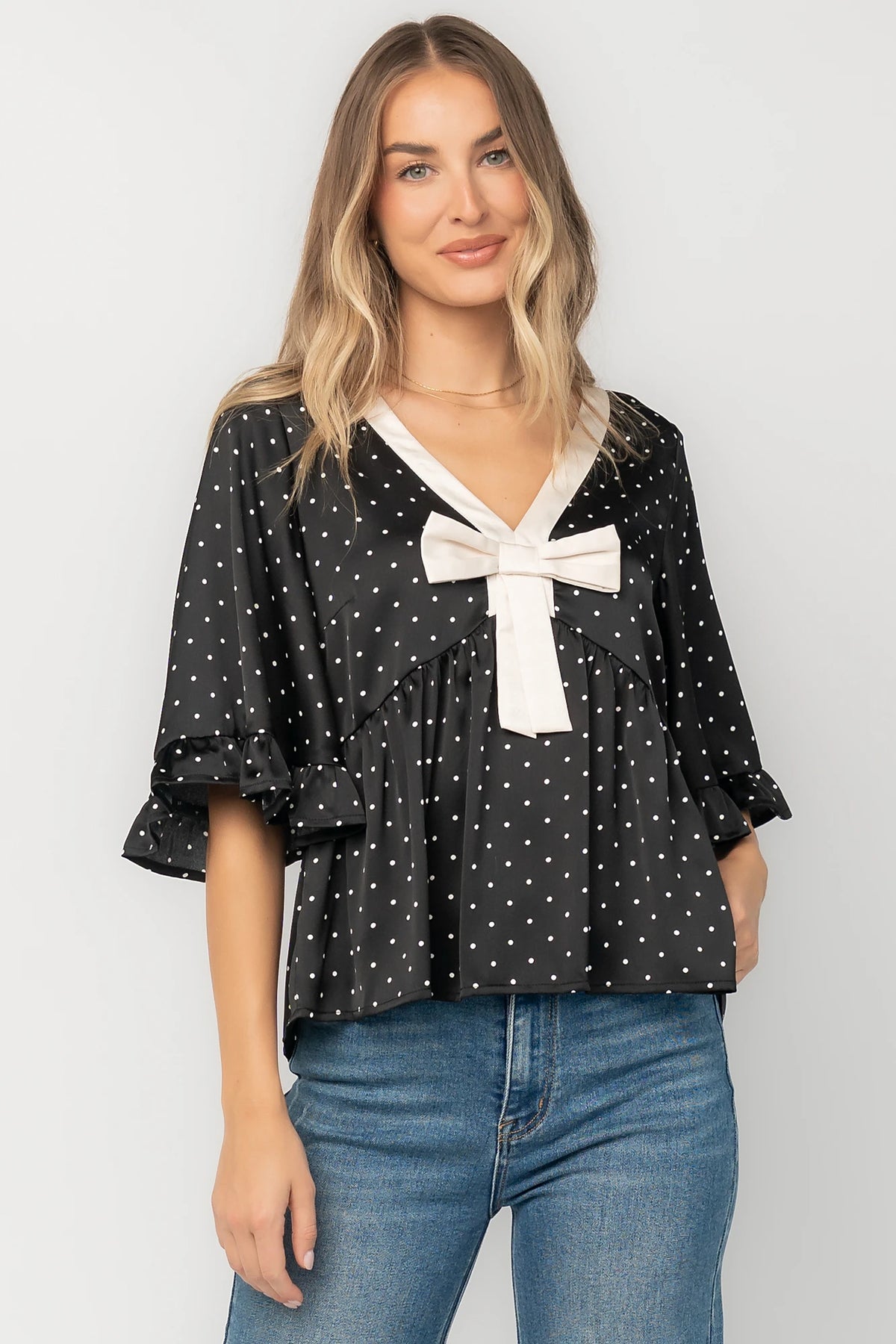 Carrie Bow Front Top in Black + Ivory Dot with contrast collar, bow detail, V-neck, ruffle sleeves, and peplum hem.