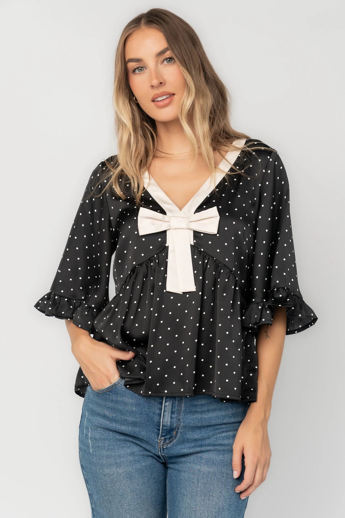 Carrie Bow Front Top in Black + Ivory Dot with contrast collar, bow detail, V-neck, ruffle sleeves, and peplum hem.
