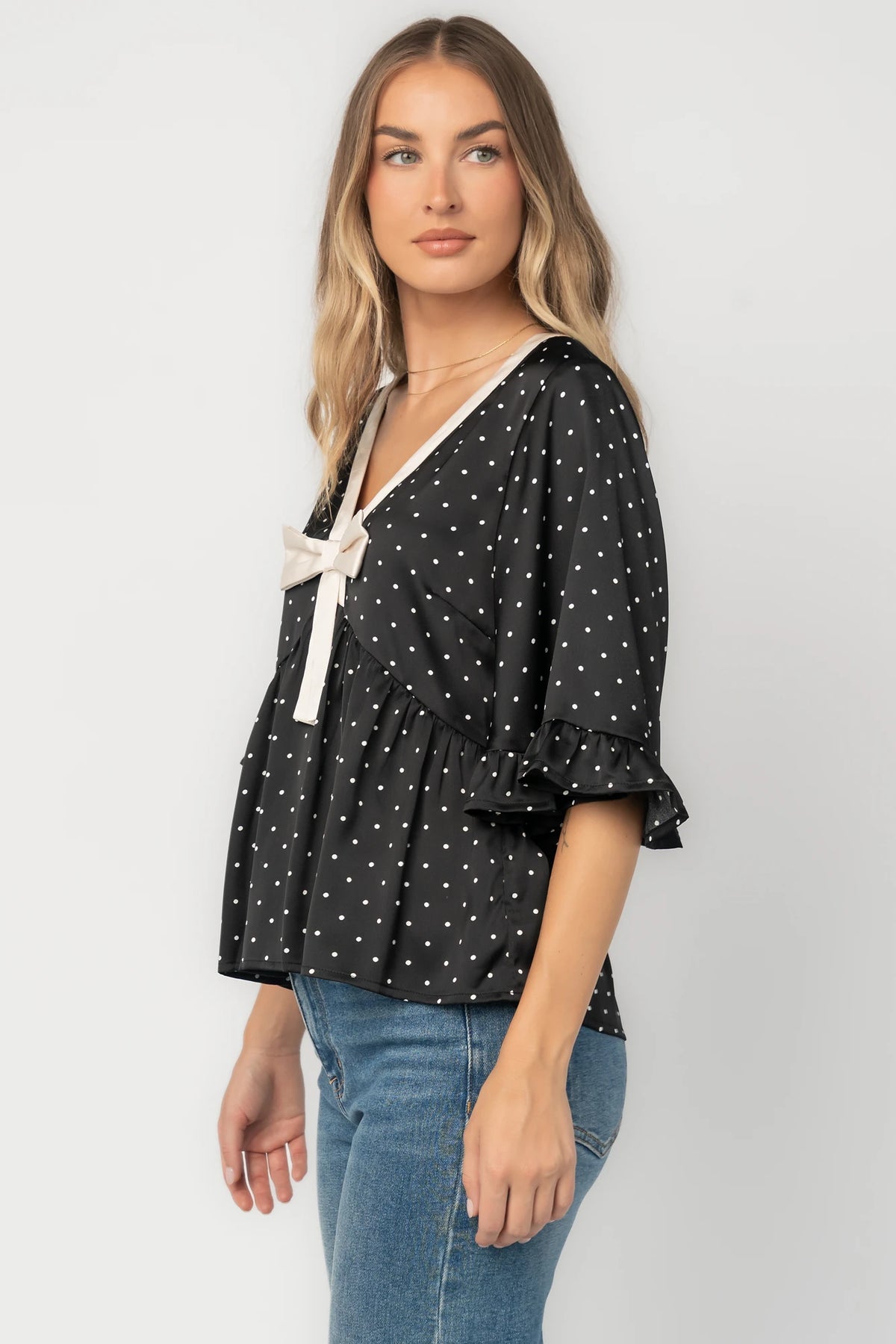 Carrie Bow Front Top in Black + Ivory Dot with contrast collar, bow detail, V-neck, ruffle sleeves, and peplum hem.