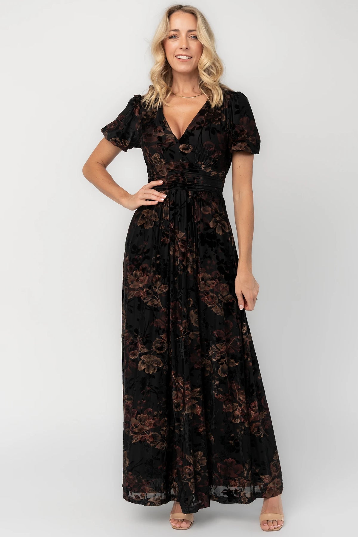 Black embossed velvet floral maxi dress with a V-neckline, short puff sleeves, gathered waist, side pockets, and a flowing full-length skirt.