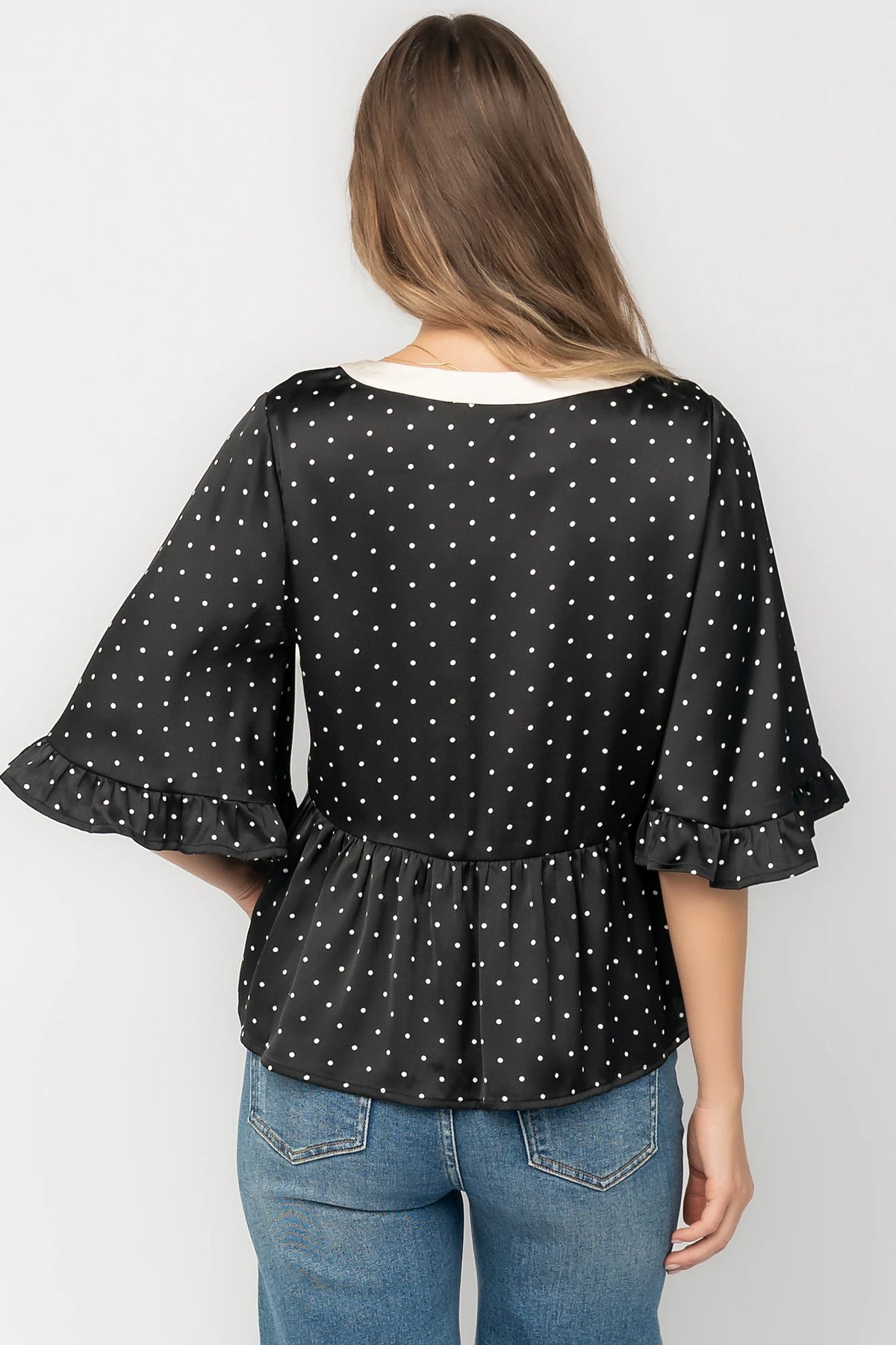 Carrie Bow Front Top in Black + Ivory Dot with contrast collar, bow detail, V-neck, ruffle sleeves, and peplum hem.
