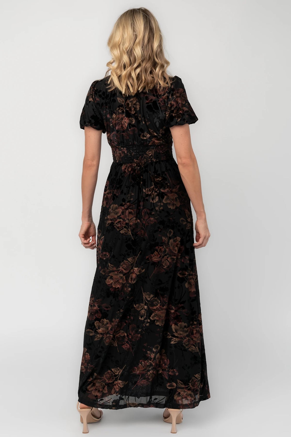 Black embossed velvet floral maxi dress with a V-neckline, short puff sleeves, gathered waist, side pockets, and a flowing full-length skirt.