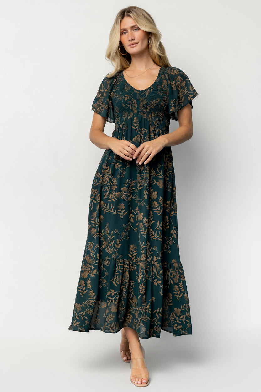 Front view of the Monica Smocked Maxi Dress in Deep Topaz with gold print on a model, showing V-neck, smocked bodice, and flowing maxi skirt.