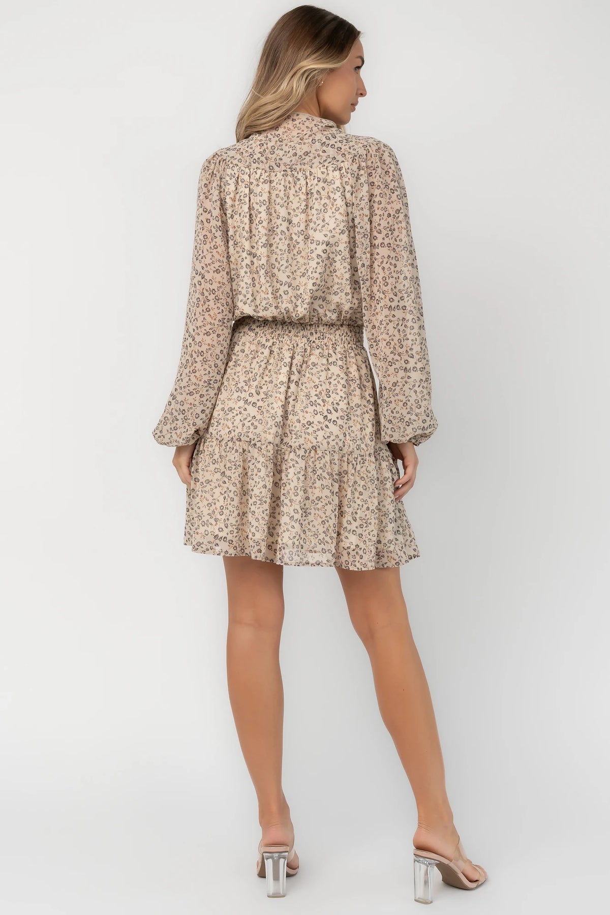 Cream floral mini dress with a self-tie neckline, cascading ruffle detail, long balloon sleeves, smocked waist, and tiered skirt.
