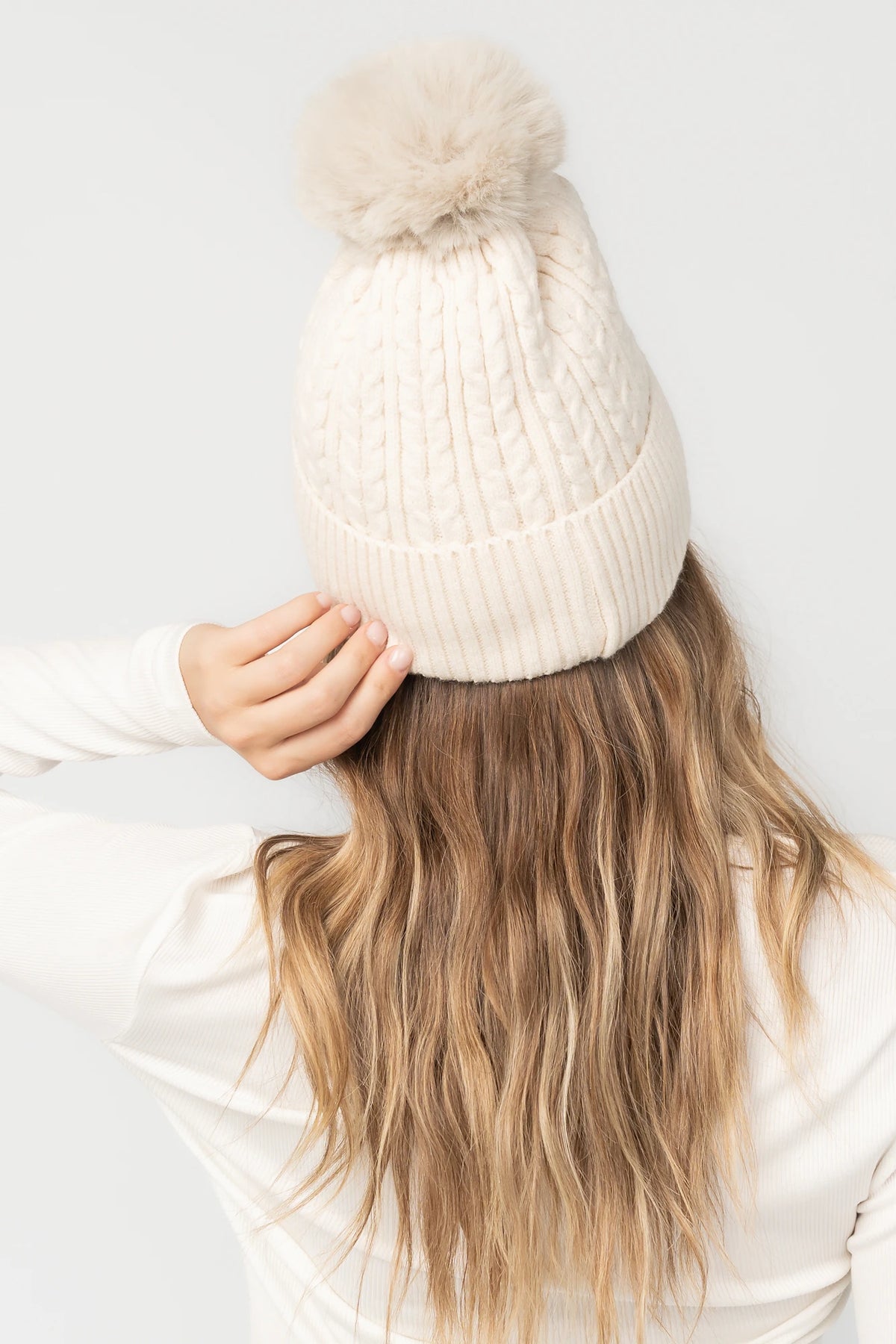 Lake Cable Knit Pom Beanie in Ivory with cable knit texture, faux fur pom, and fold-over ribbed cuff.
