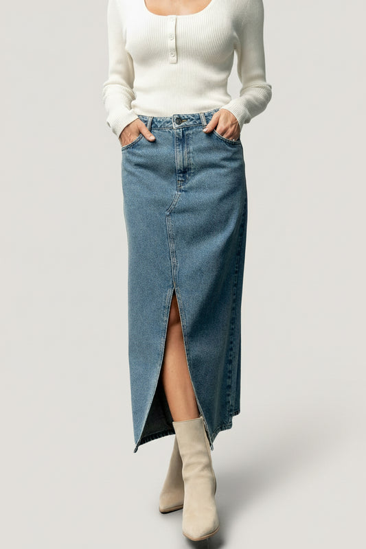 Front view of medium wash Aleksa denim midi skirt on model, showing center-front slit, high-rise waist, and functional pockets.