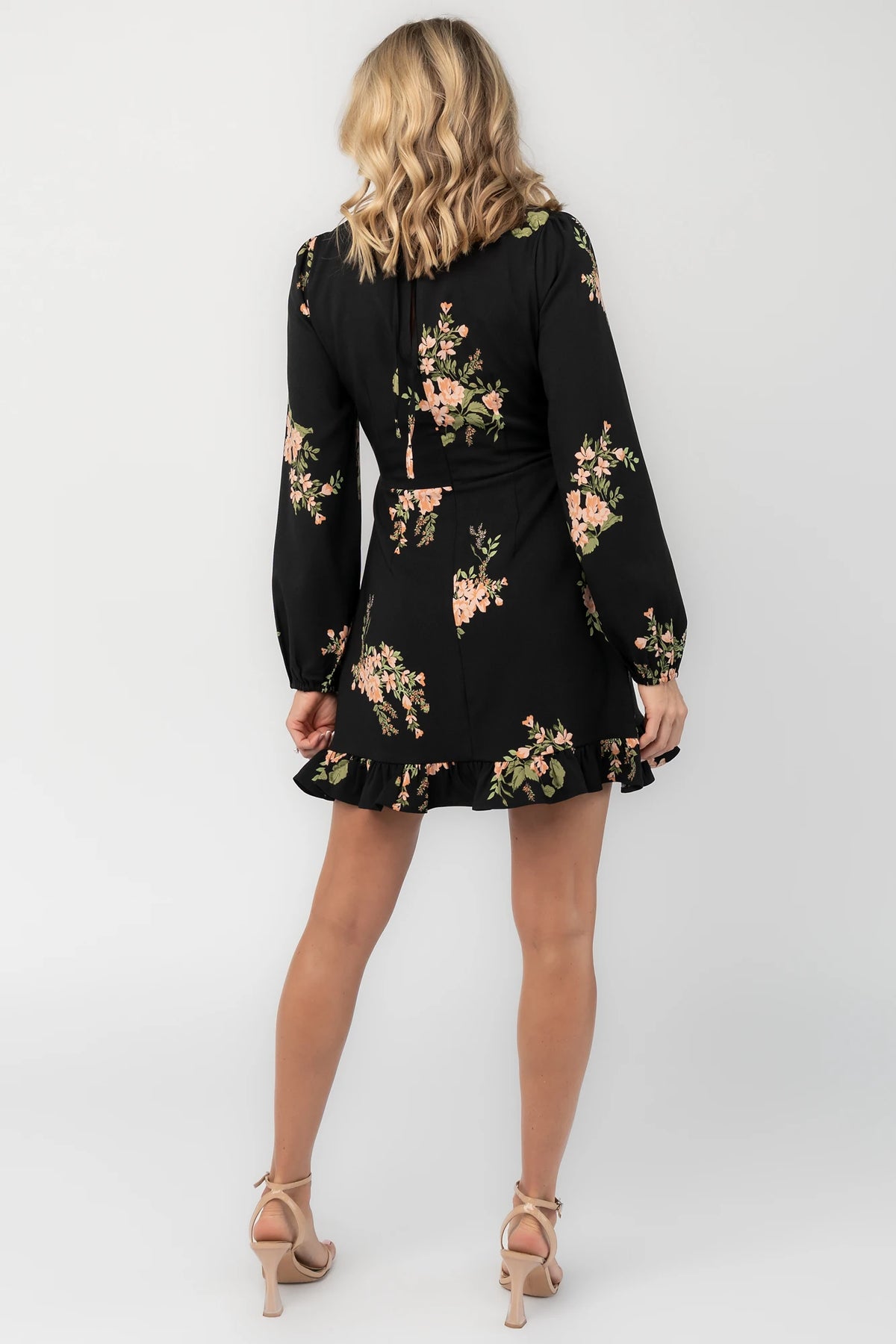 Black floral mini dress with a round neckline, long sleeves, fitted bodice, ruffle hem, back keyhole tie, and hidden back zipper.