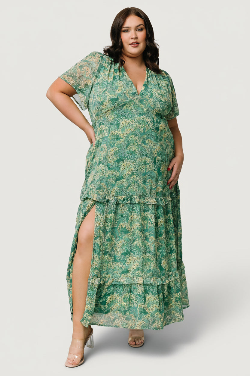 Side-angle of model in green floral chiffon maxi dress highlighting tiered ruffles, soft drape and the subtle leg slit for movement.