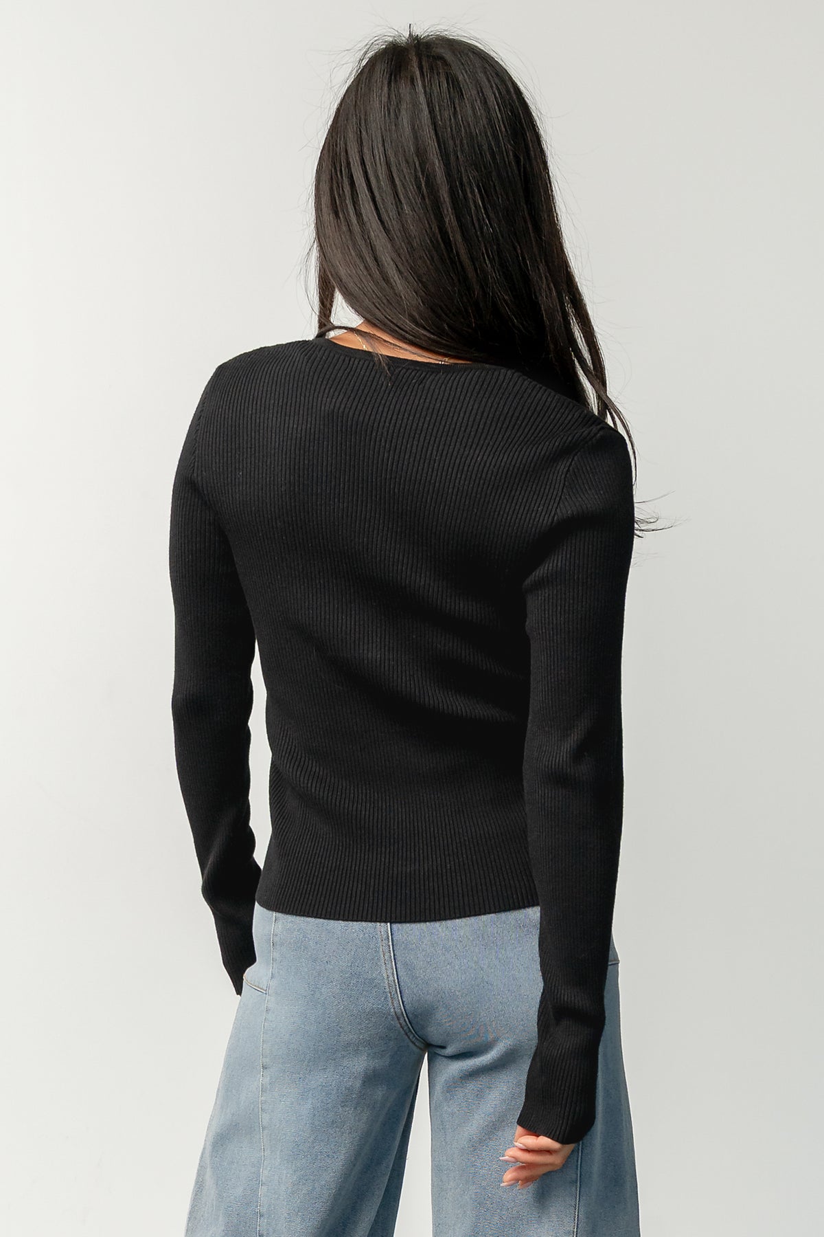 Styled flat-lay of the Leo Ribbed Henley Top in black paired with mid-rise wide leg jeans, showing neckline and hem proportions.