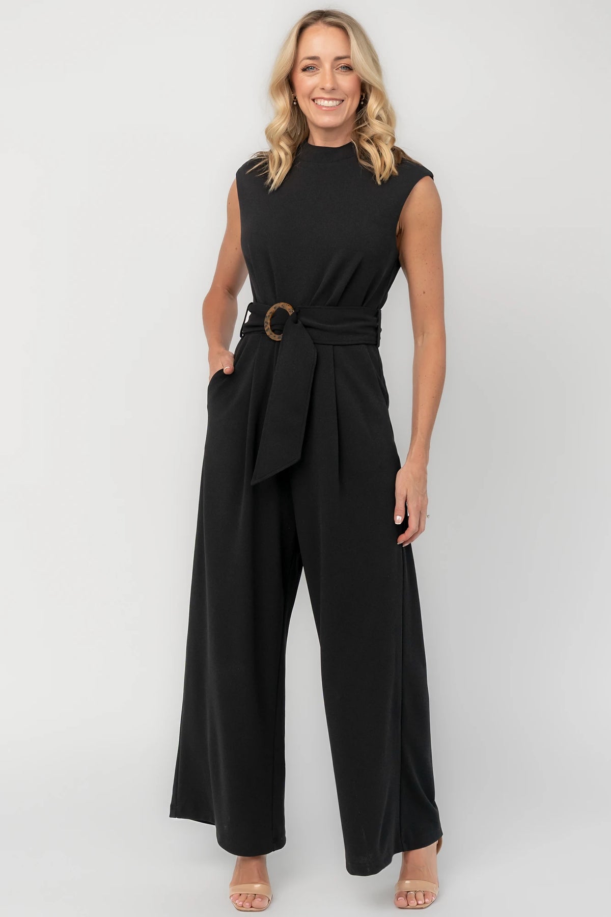 Black wide-leg jumpsuit with a mock neckline, cap sleeves, attached tortoise buckle waist tie, back zipper, and side pockets.