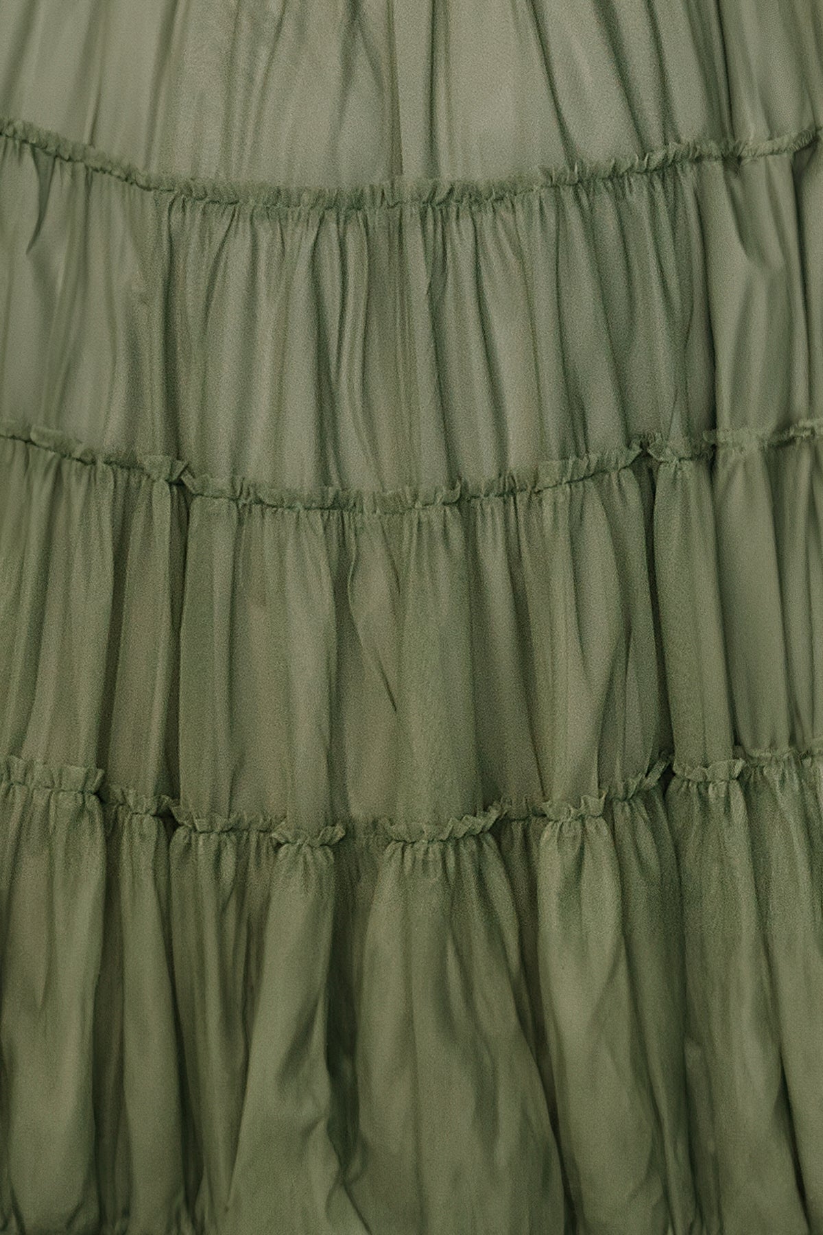 Close-up of a small sage tulle fabric swatch for the Emma dress, showing fine netted texture and soft sage color on a white background.