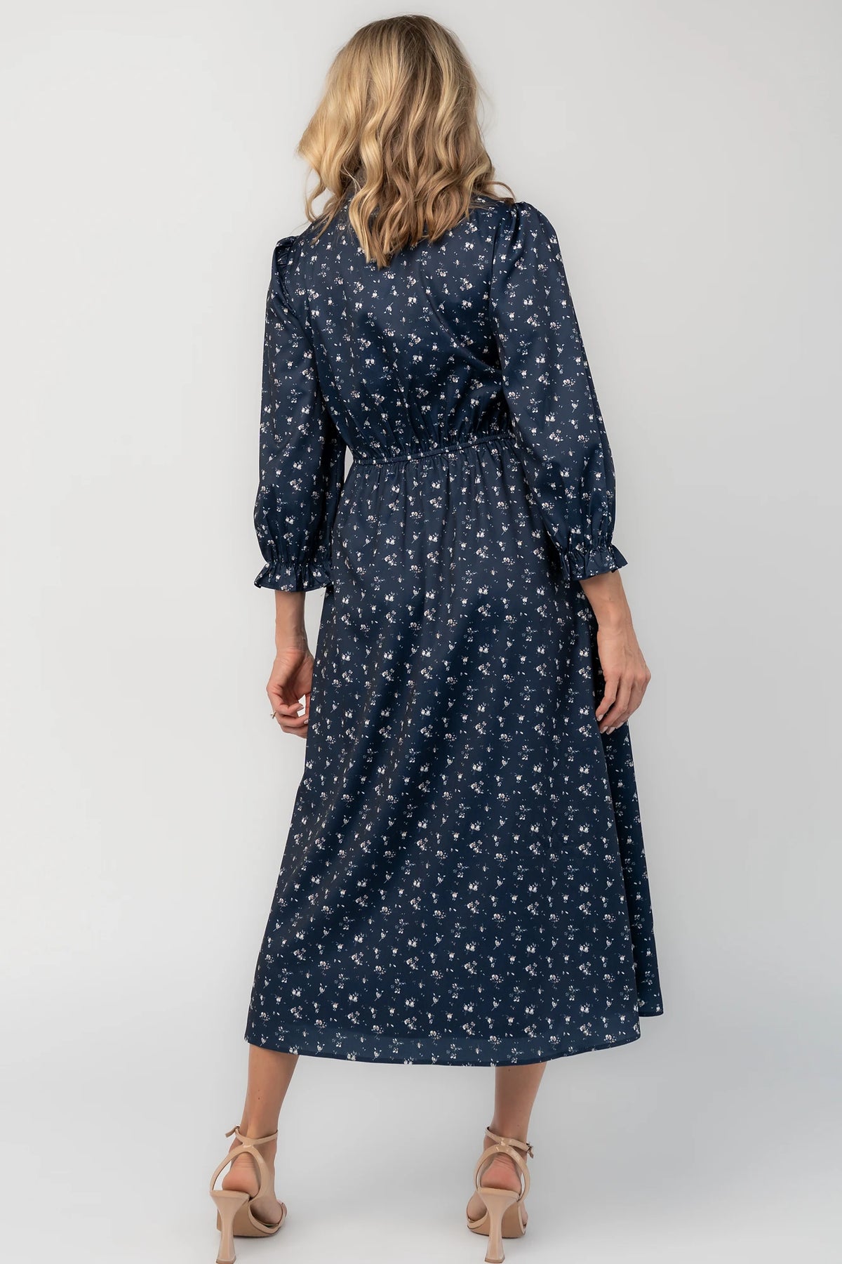 Navy floral button-down midi dress with a collared neckline, smocked bodice, three-quarter sleeves, elastic back waist, side pockets, and a flowing skirt.