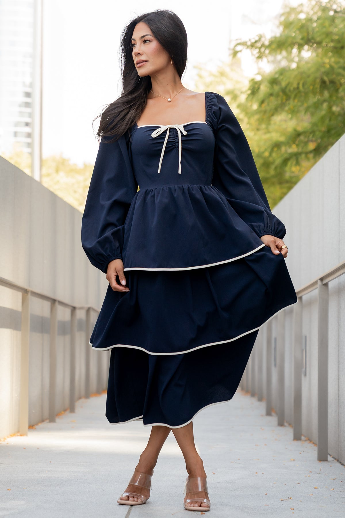 Close-up of the gathered center bust seam, decorative bow, and ivory accent trim on the navy Barcelona tiered dress.