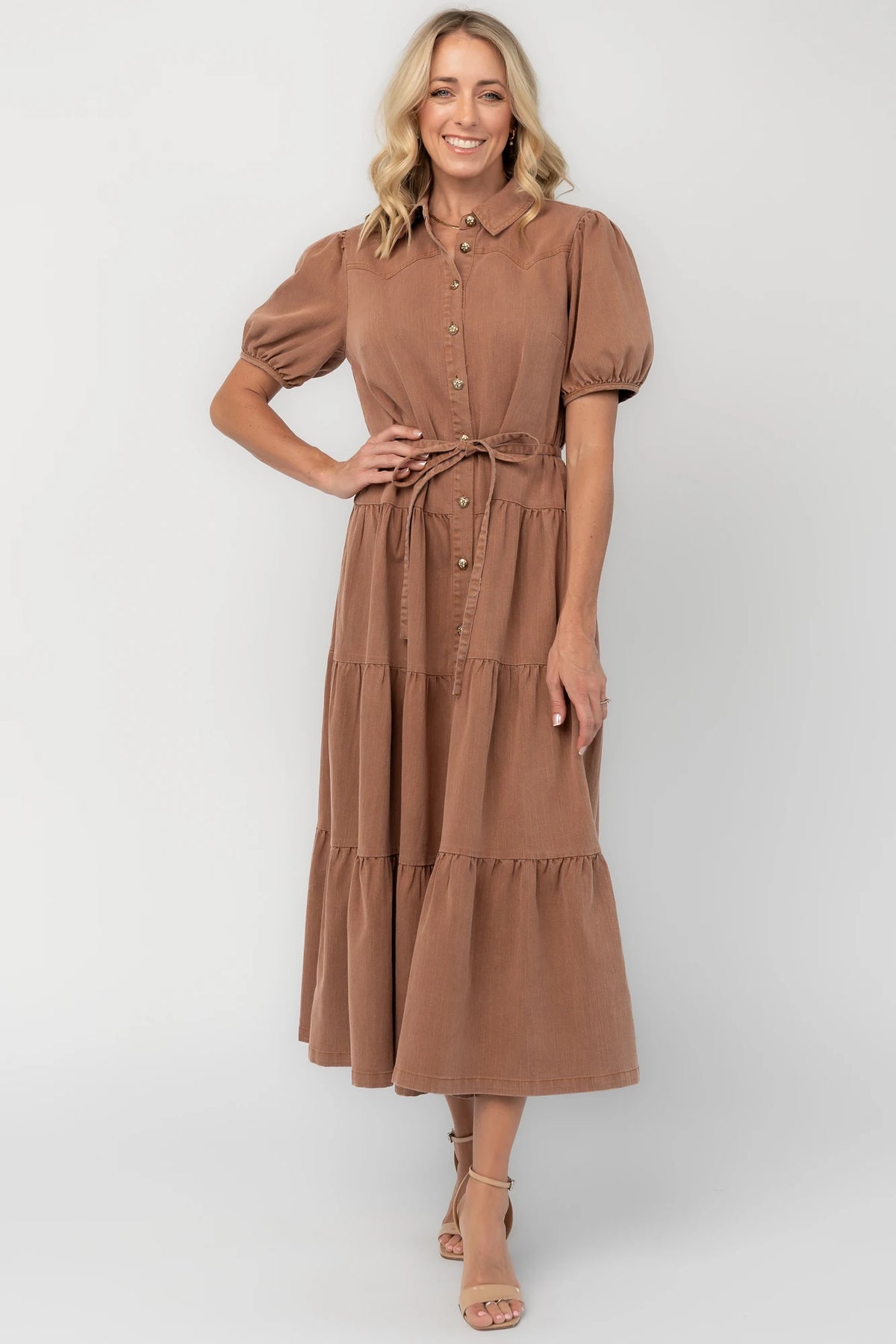 Dusty mocha midi dress with a collared neckline, gold-tone button-front closure, short puff sleeves, removable waist tie, and tiered skirt.
