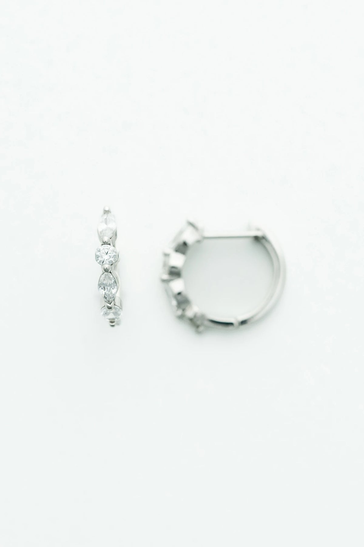 Silver hoop earrings adorned with clear crystal stones in mixed round and marquise shapes.
