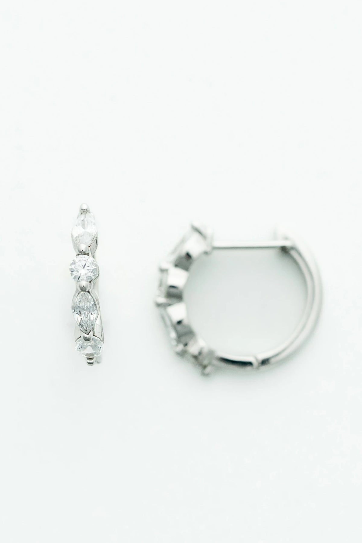 Silver hoop earrings adorned with clear crystal stones in mixed round and marquise shapes.