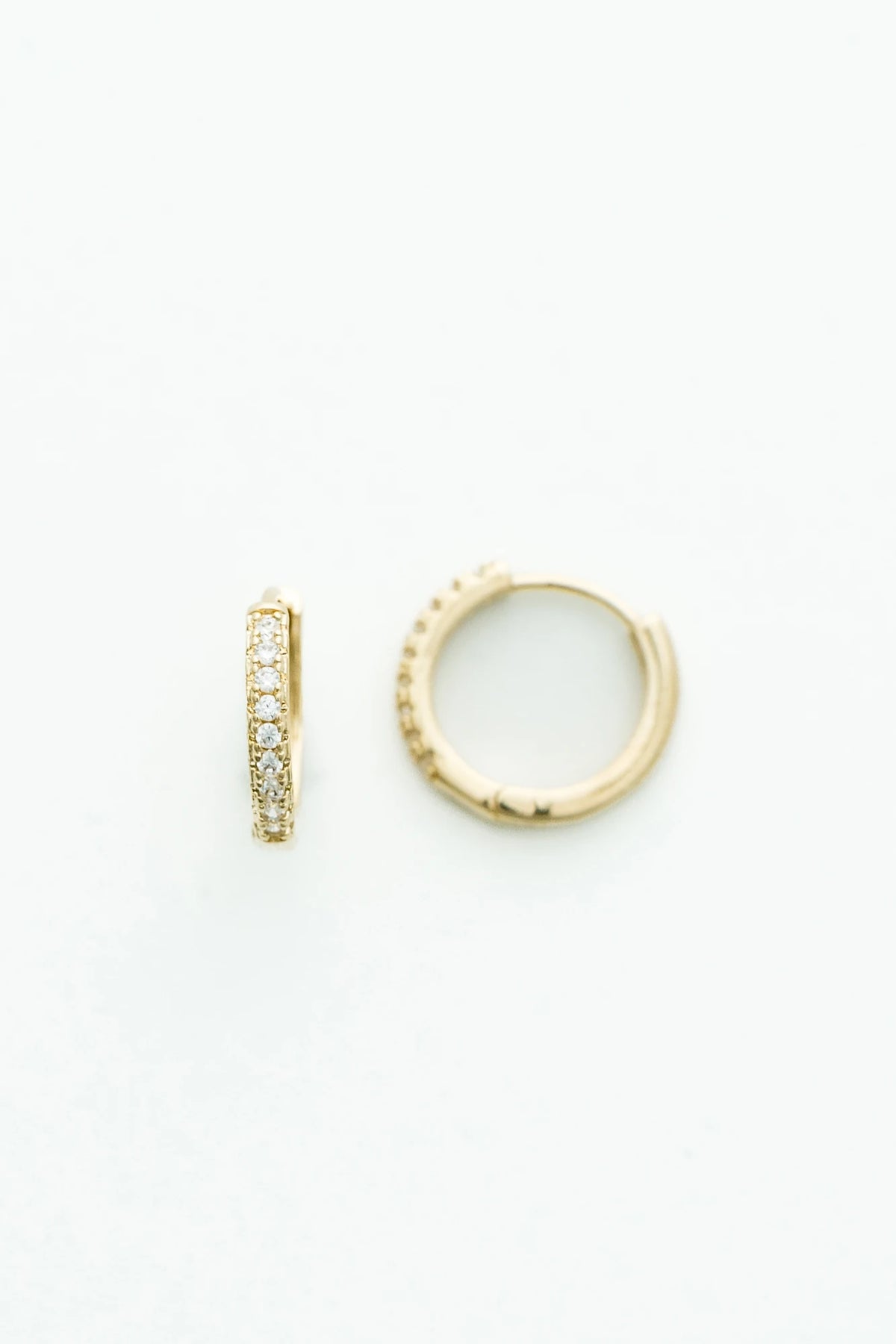 Gold-tone huggie hoop earrings accented with a row of sparkling crystal stones along the front. 