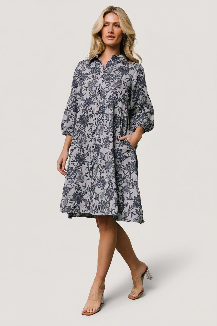 Front view of Dakota navy botanical babydoll dress on model, showing full button-front, tiered short skirt and roomy side pockets.