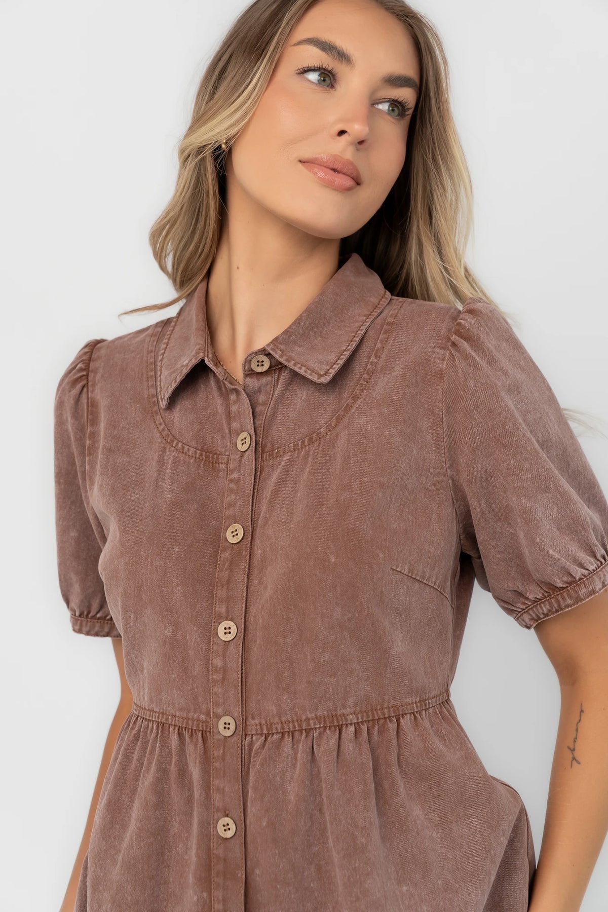 Dusty mocha mineral wash mini dress with a collared neckline, button-front closure, short puff sleeves, empire waist, and relaxed silhouette.
