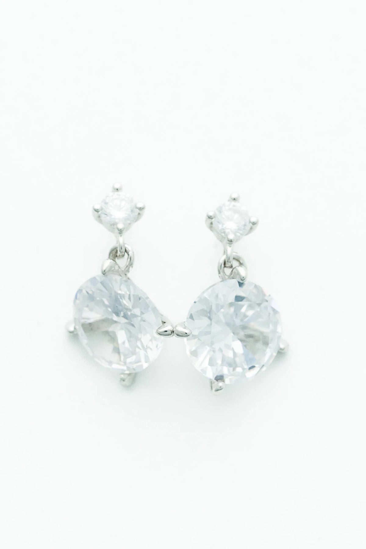Silver-tone drop earrings featuring sparkling round zircon stones suspended from petite stud tops.