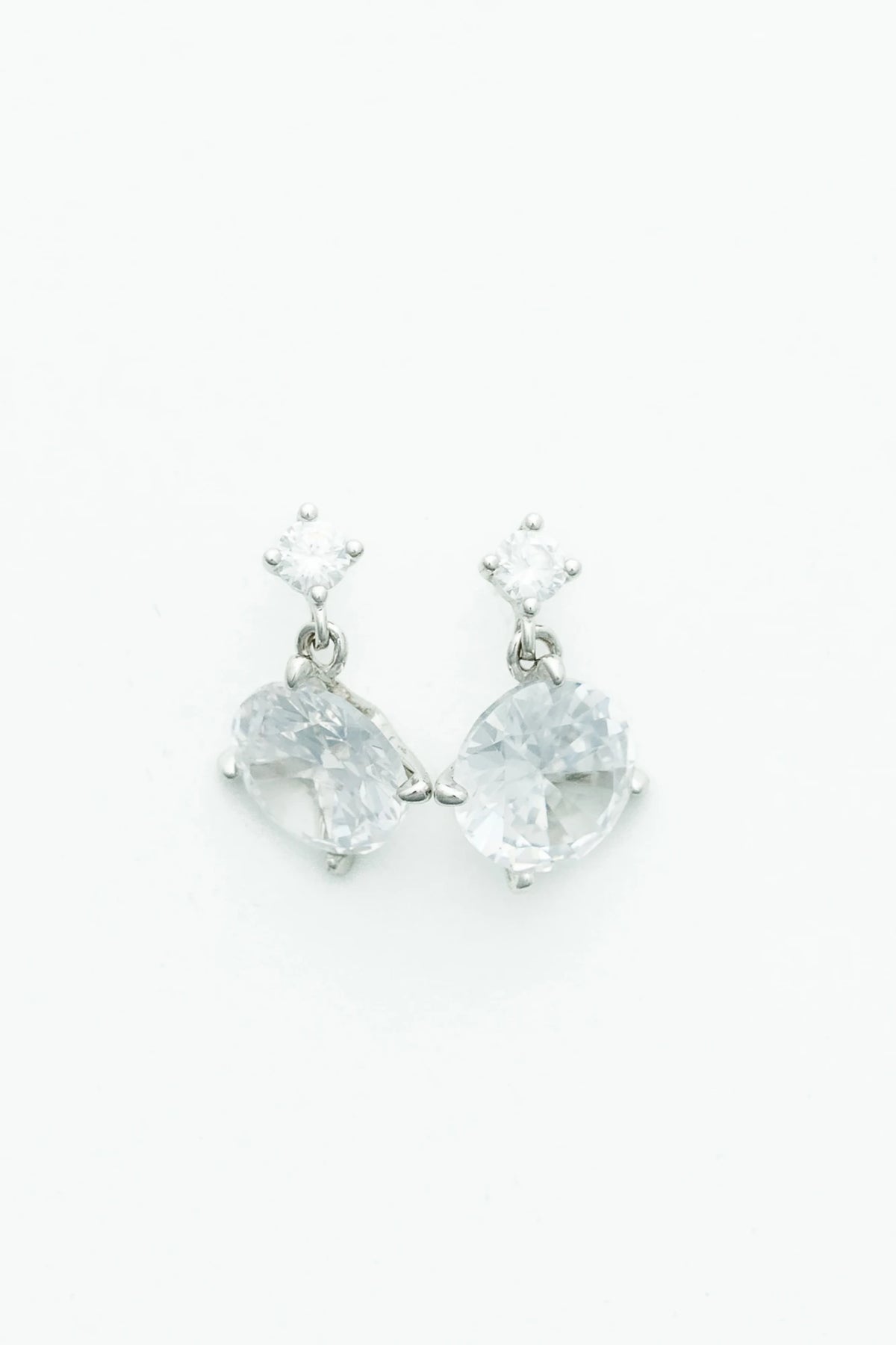 Silver-tone drop earrings featuring sparkling round zircon stones suspended from petite stud tops.