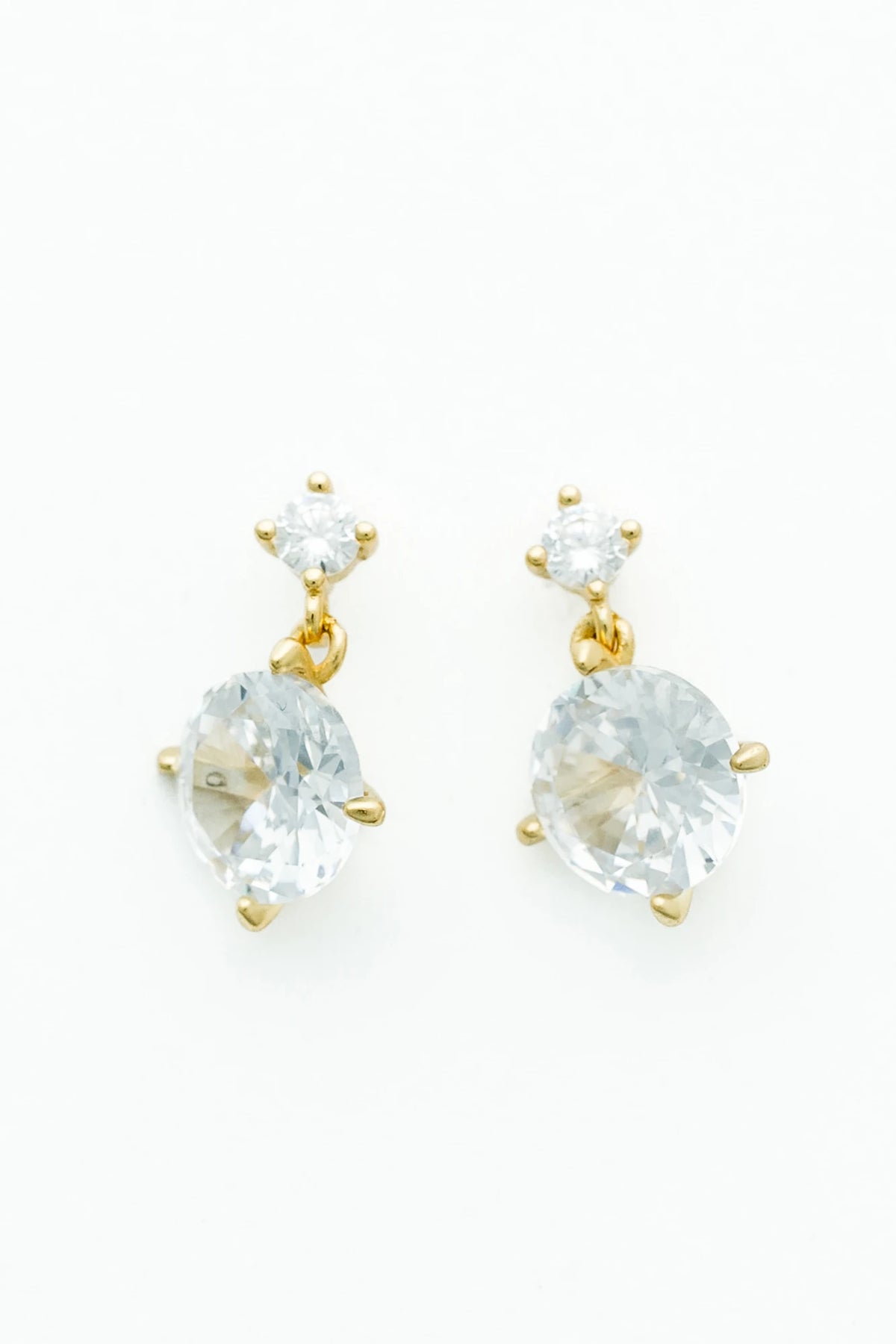 Gold-tone drop earrings featuring sparkling round zircon stones suspended from petite stud tops.