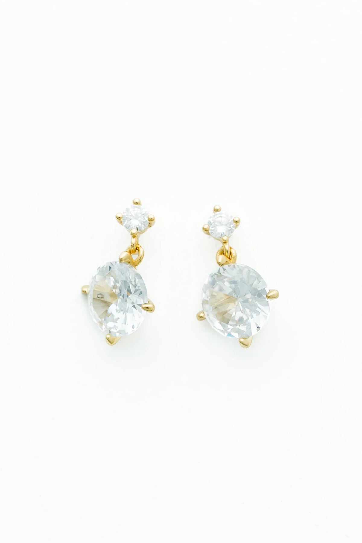 Gold-tone drop earrings featuring sparkling round zircon stones suspended from petite stud tops.