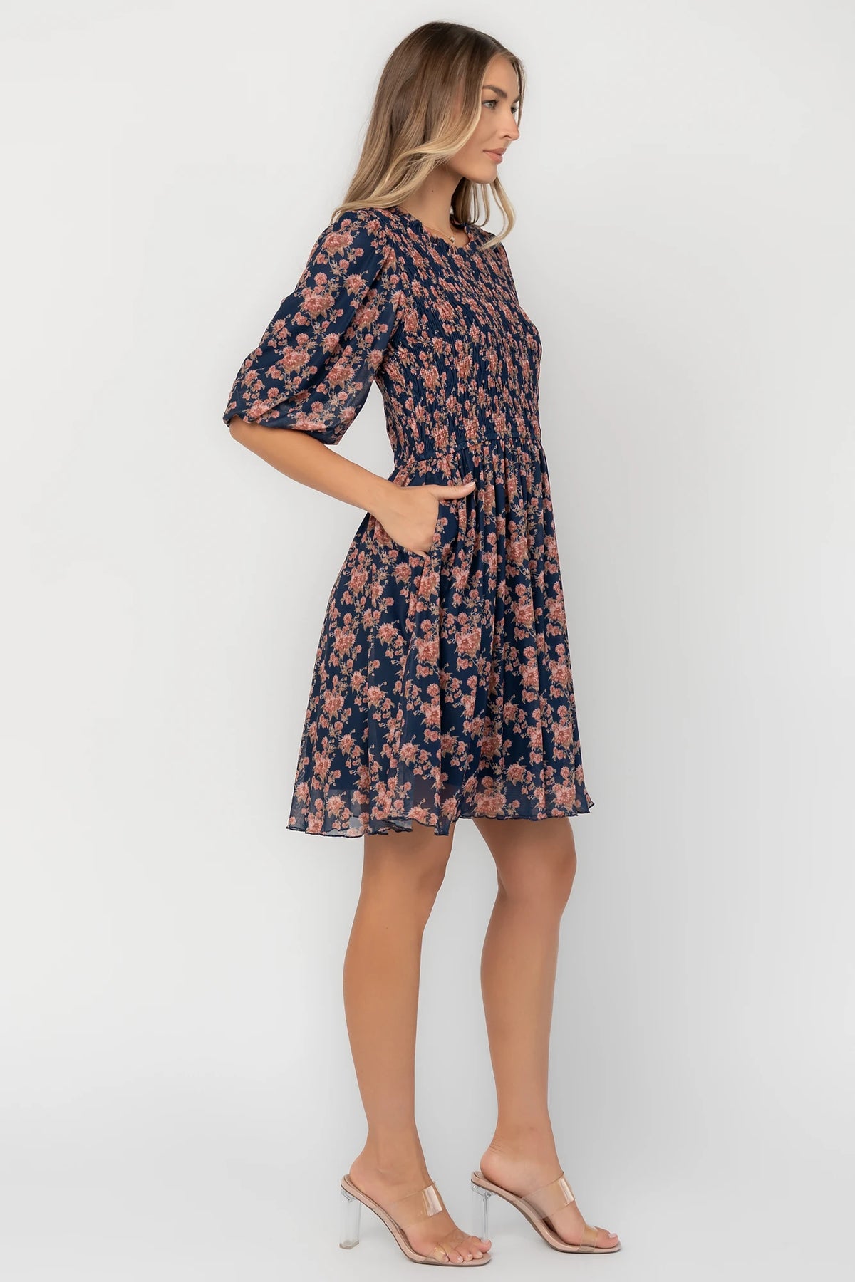 Navy floral mesh mini dress with a round neckline, elbow-length sleeves, smocked bodice, side pockets, and a flowy skirt.
