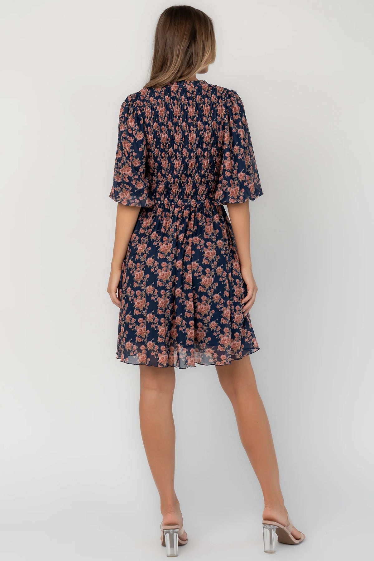 Navy floral mesh mini dress with a round neckline, elbow-length sleeves, smocked bodice, side pockets, and a flowy skirt.