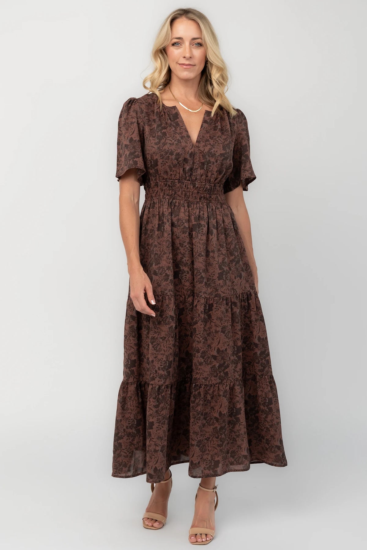 Espresso floral maxi dress with a split V-neckline, flutter sleeves, smocked waist, and flowing tiered skirt.