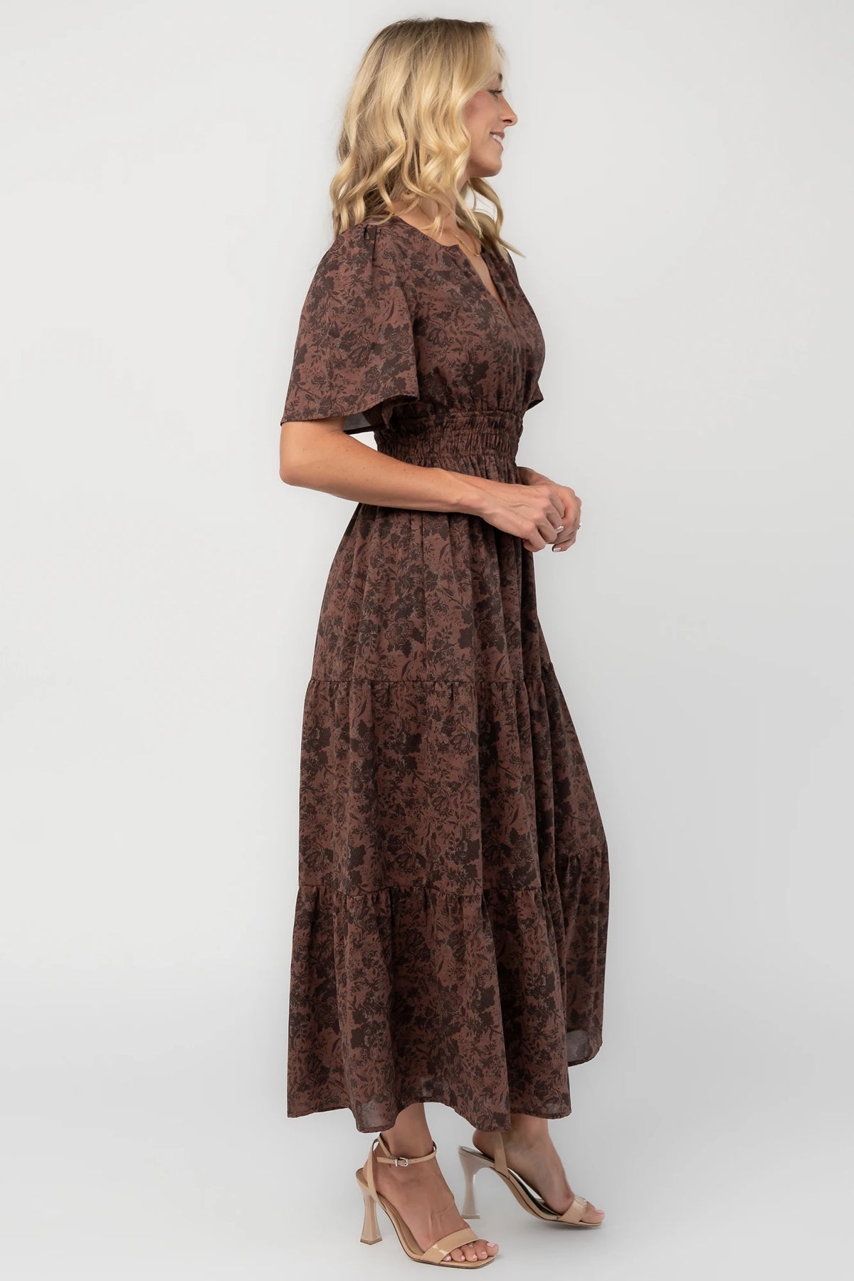 Espresso floral maxi dress with a split V-neckline, flutter sleeves, smocked waist, and flowing tiered skirt.