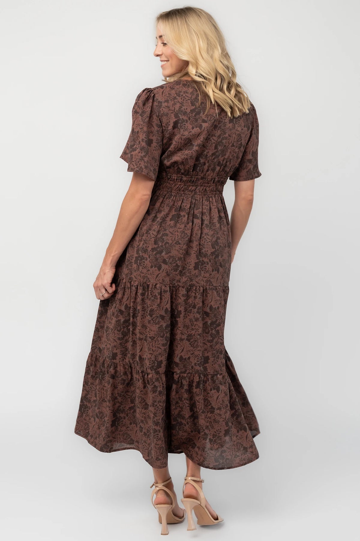 Espresso floral maxi dress with a split V-neckline, flutter sleeves, smocked waist, and flowing tiered skirt.