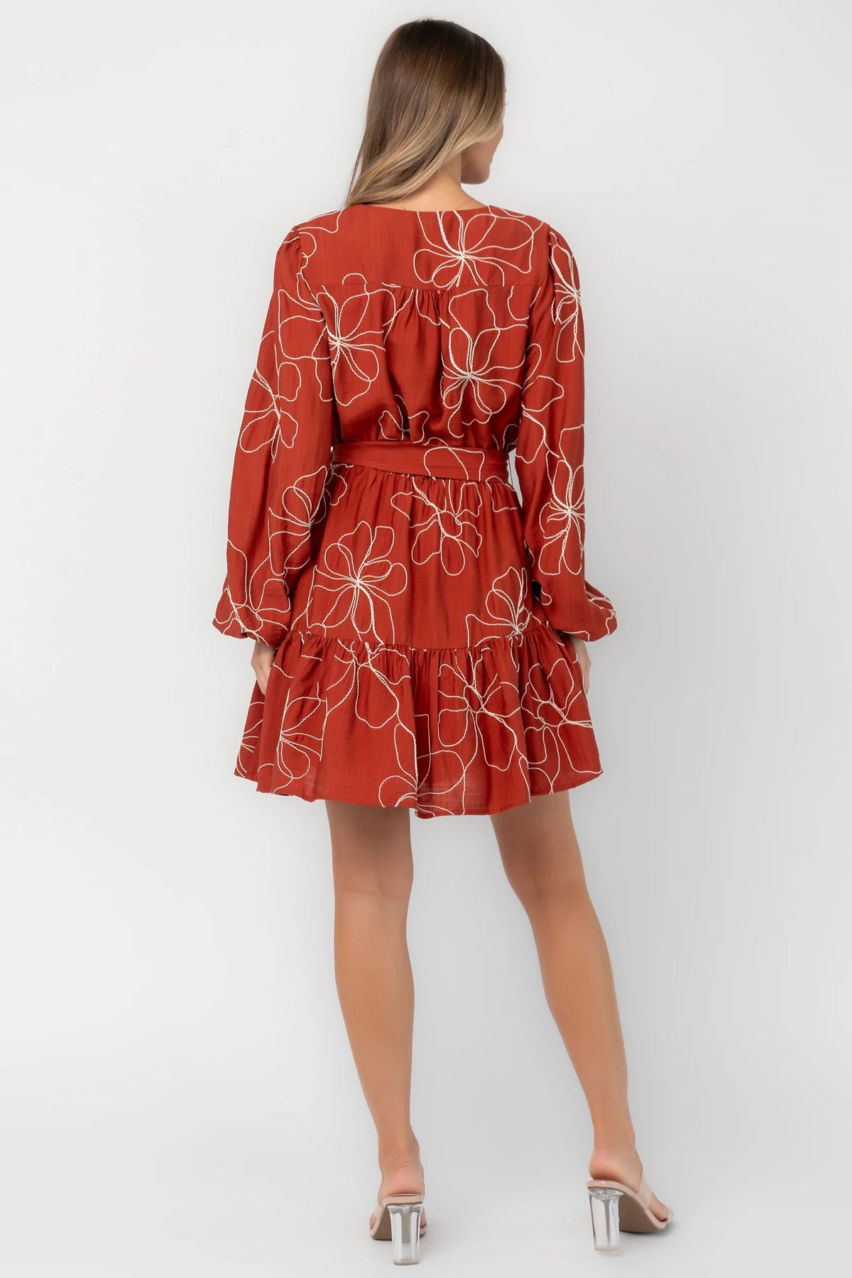 Rust floral mini dress with a V-neckline, button-front bodice, long balloon sleeves, elastic waistband with a self-tie sash, tiered ruffle hem, and side pockets.