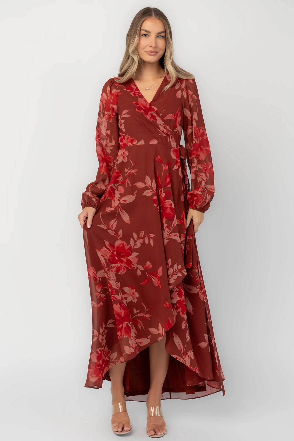 Rust multi floral chiffon maxi dress with a faux wrap neckline, long balloon sleeves, adjustable waist tie, and a high-low skirt.