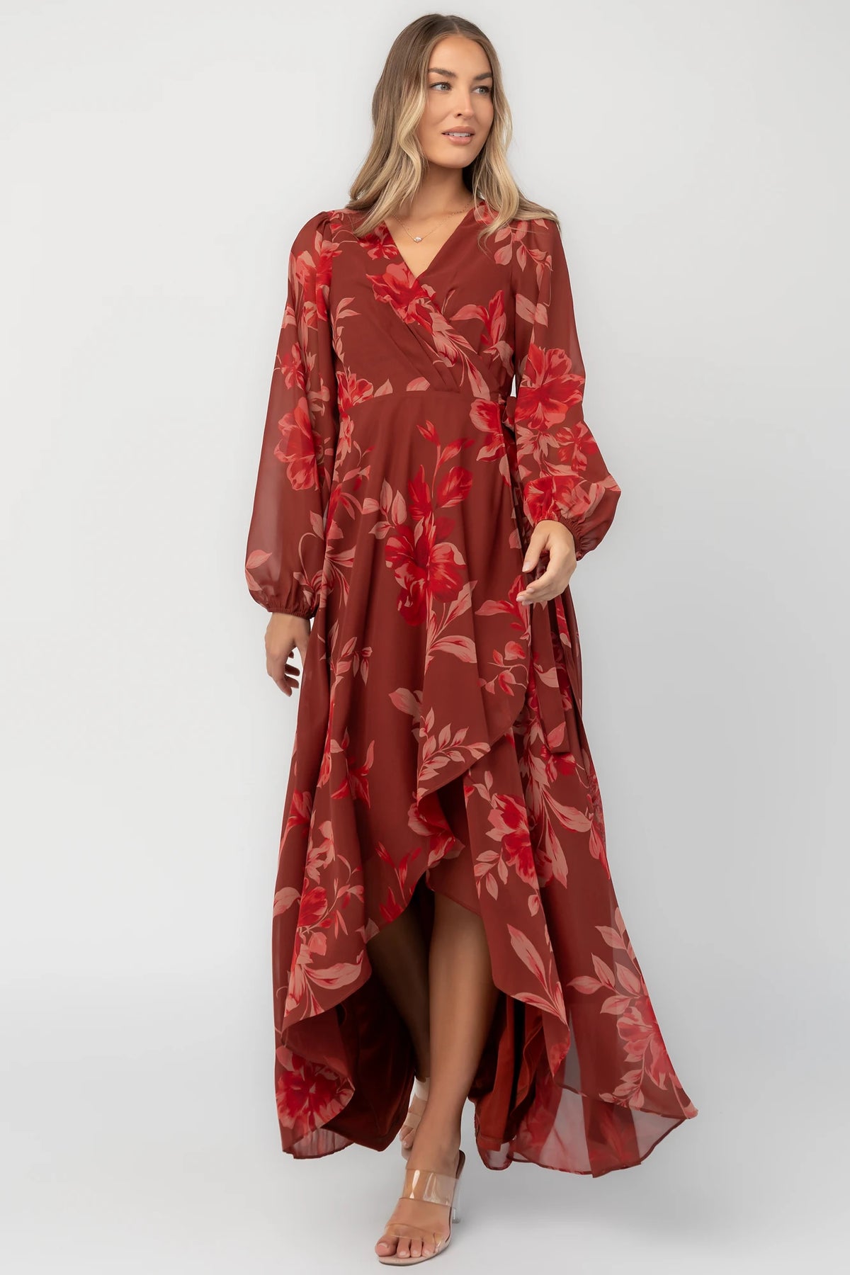 Rust multi floral chiffon maxi dress with a faux wrap neckline, long balloon sleeves, adjustable waist tie, and a high-low skirt.