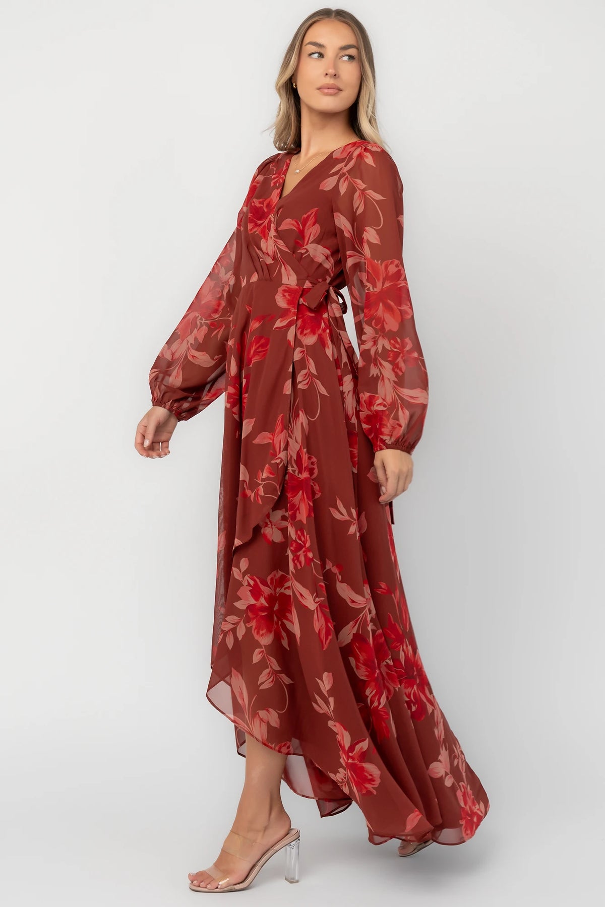 Rust multi floral chiffon maxi dress with a faux wrap neckline, long balloon sleeves, adjustable waist tie, and a high-low skirt.