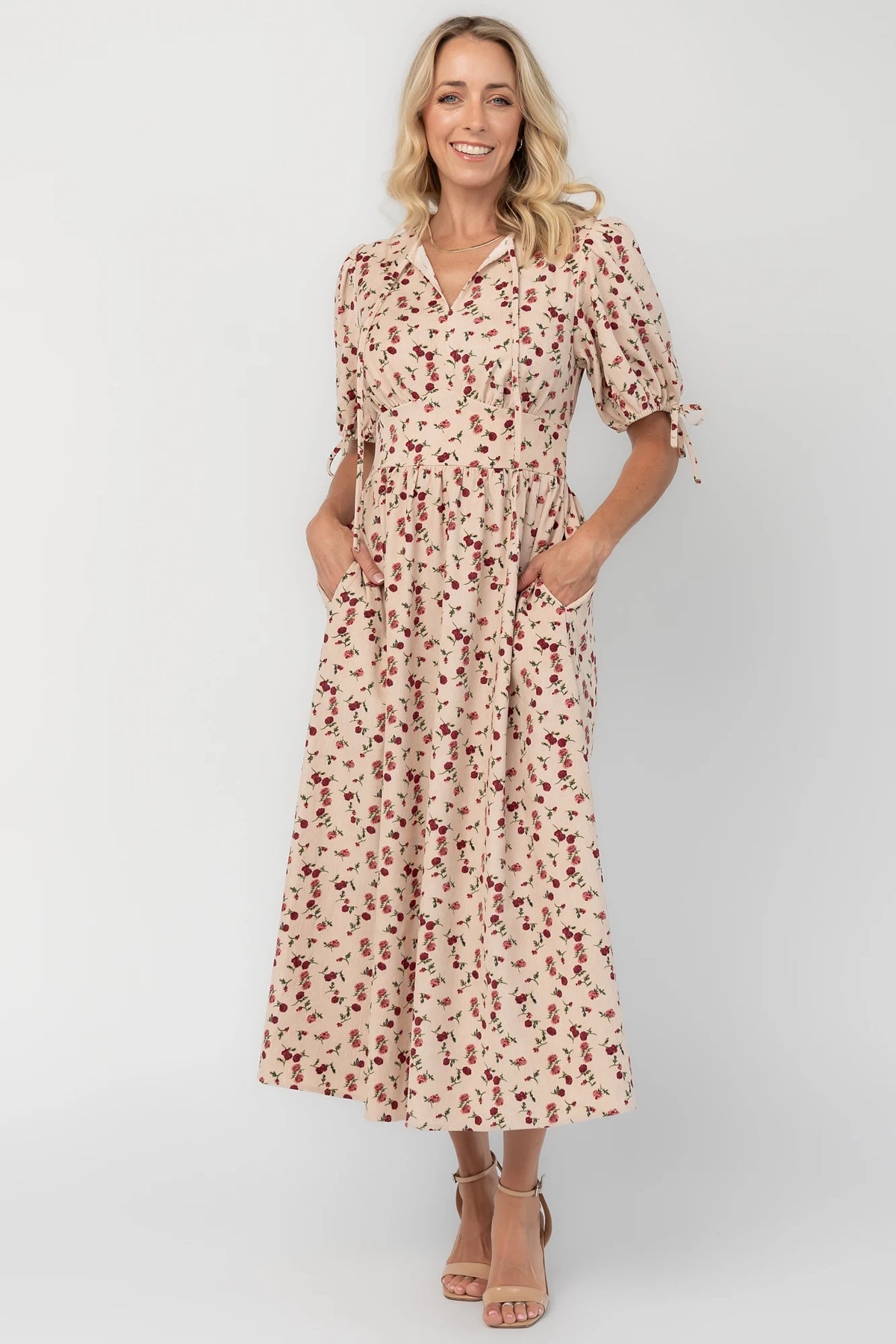 Ivory floral textured midi dress with a split V-neckline, short puff sleeves, empire waist, smocked back, side pockets, and a flowing skirt.