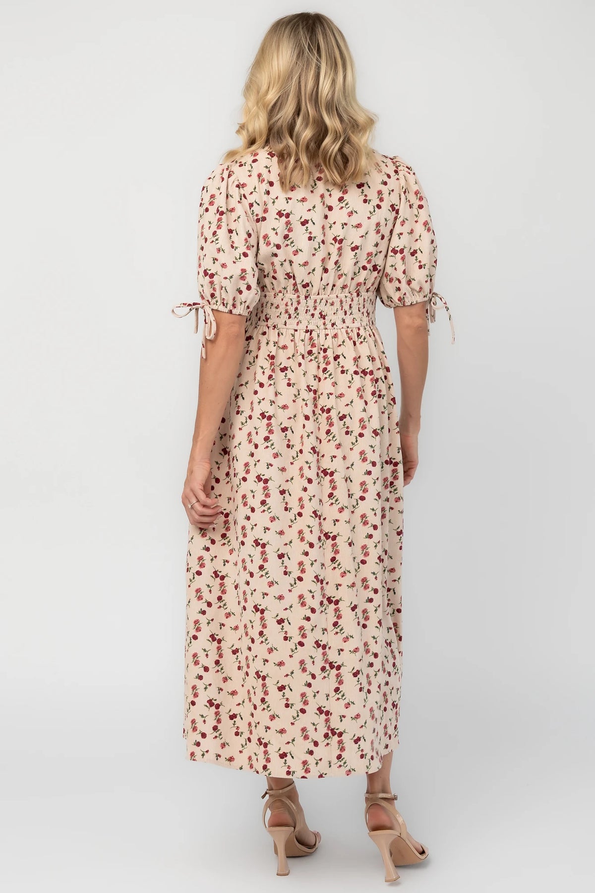Ivory floral textured midi dress with a split V-neckline, short puff sleeves, empire waist, smocked back, side pockets, and a flowing skirt.