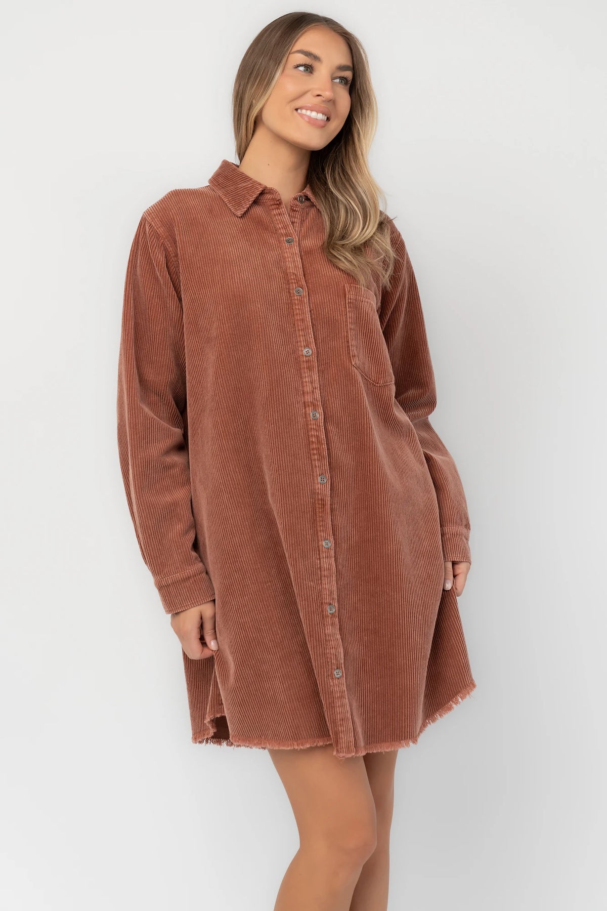 Dusty clay corduroy button-front shirt jacket with a collared neckline, oversized fit, chest pocket, long sleeves, and a rounded high-low hem.