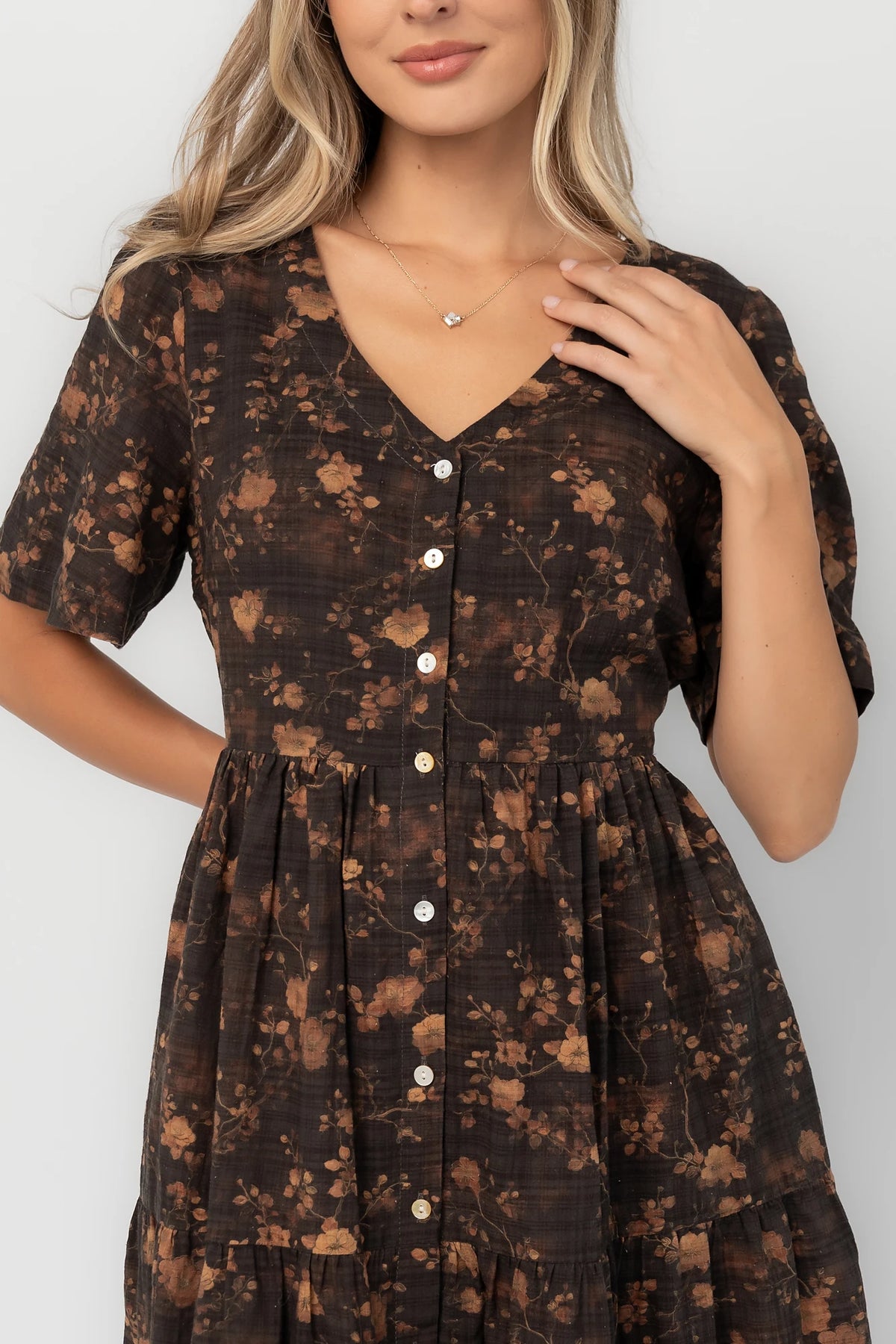 Clove floral midi dress with a V-neckline, functional button-front closure, puff sleeves, elastic back waist, side pockets, and a tiered skirt.