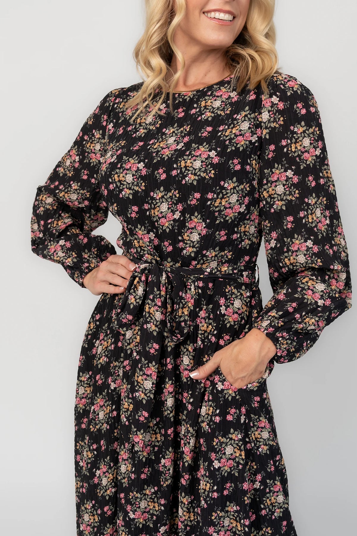 Floral midi dress with a round neckline, long sleeves, smocked back bodice, removable waist tie, tiered skirt, and back keyhole closure.